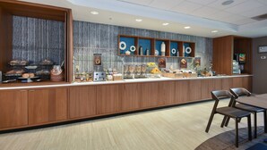 A breakfast bar with a marble backsplash, wooden cabinets, and a variety of food items and beverages. - SpringHill Suites by Marriott Charlotte Concord Mills Spdwy (Concord)