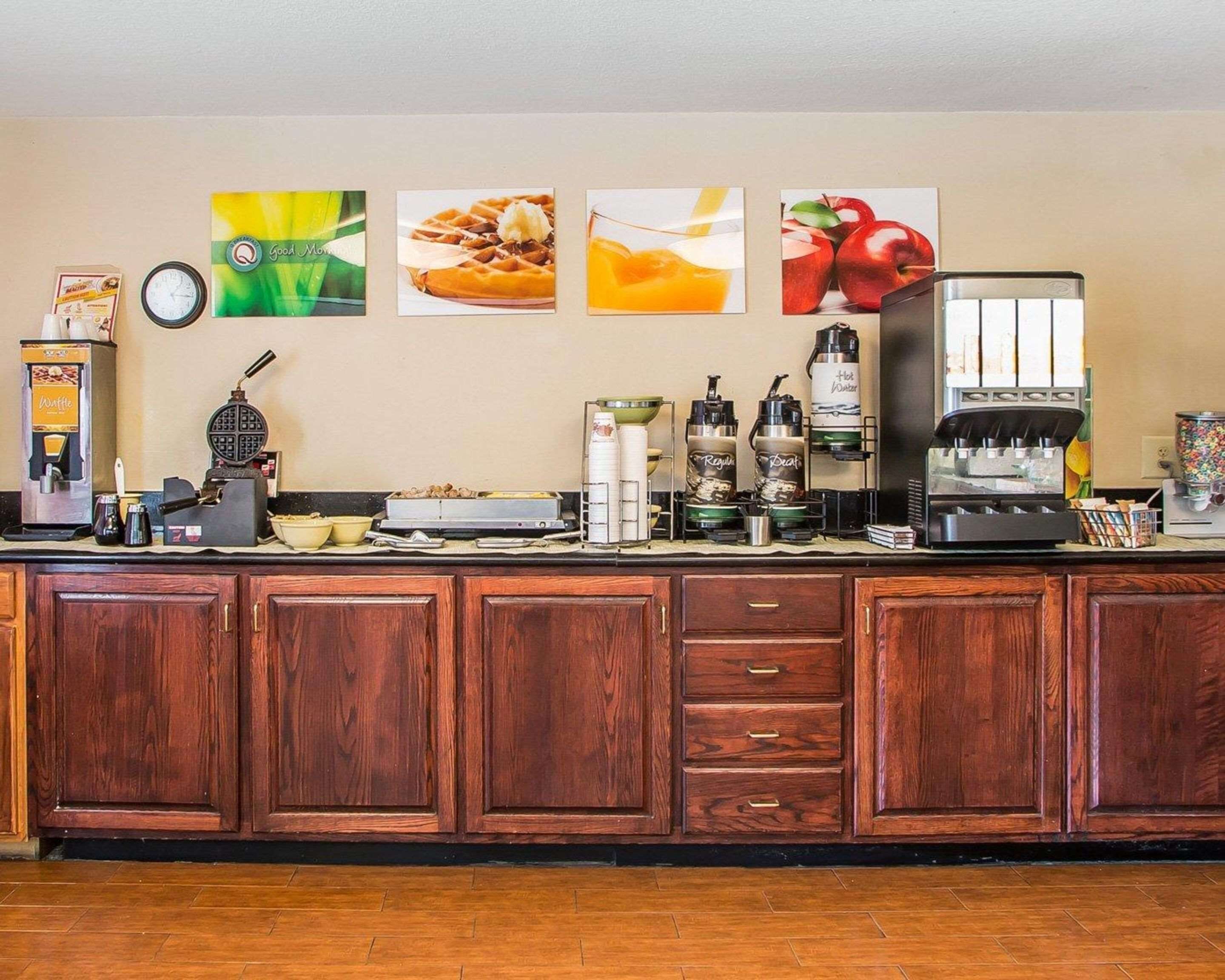 Una zona de cocina con una máquina para gofres, cafeteras y un reloj en la pared.