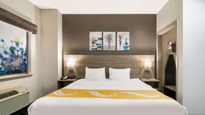 Une chambre d’hôtel avec un grand lit, deux lampes de chevet, une tête de lit en bois et une œuvre d’art accrochée au mur.