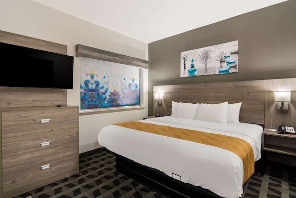 Quarto de hotel com cama, televisão, cômoda e obras de arte nas paredes.