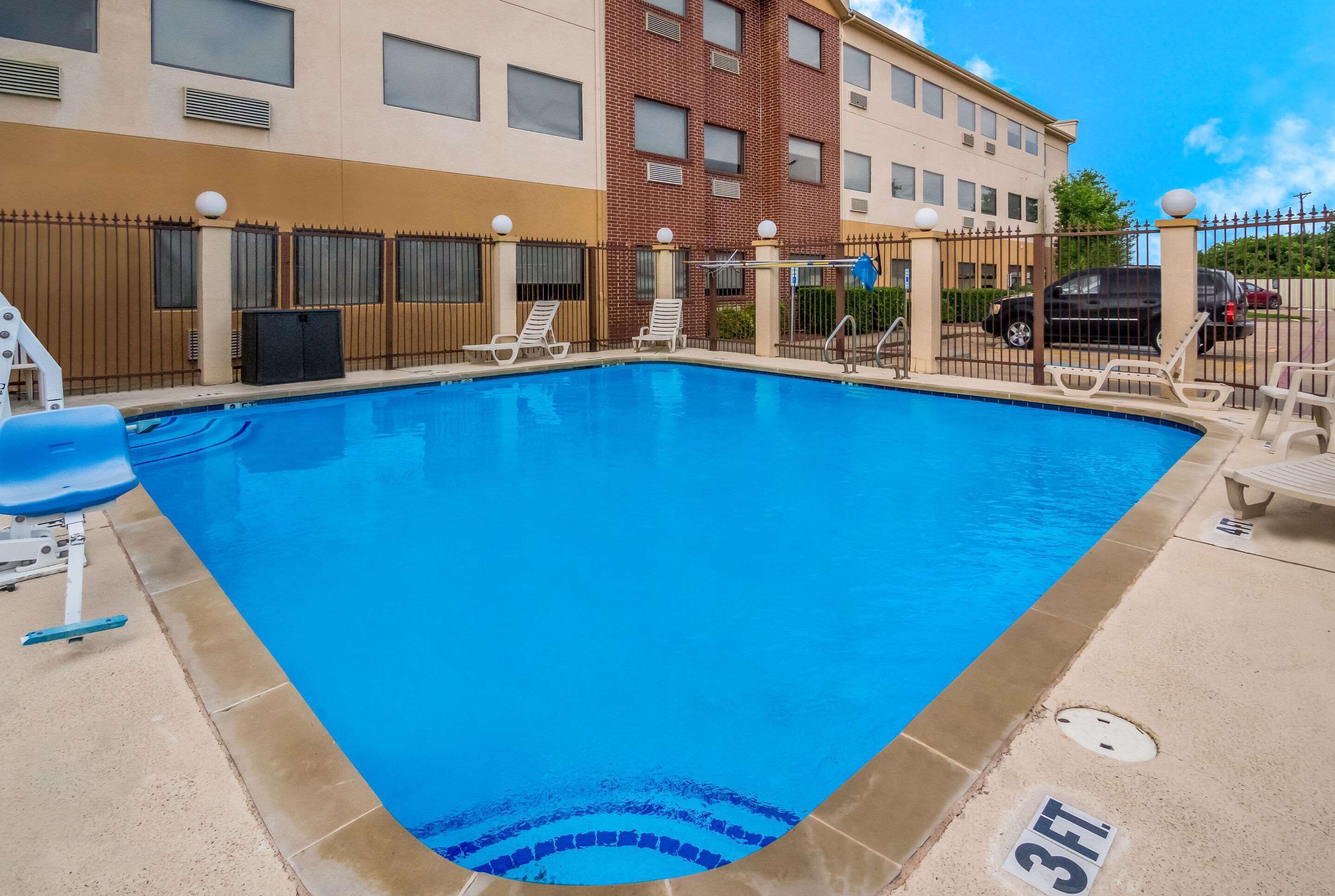 A swimming pool with lounge chairs, a 3ft depth marker, and a fenced area.