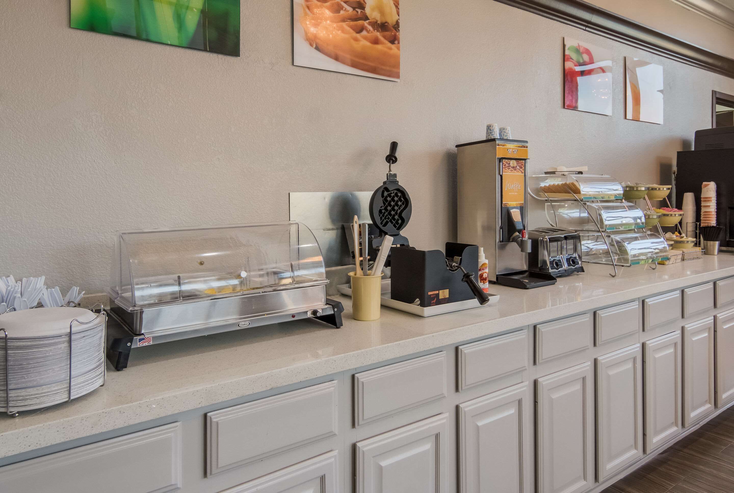 A buffet counter with a waffle maker, condiment dispensers, and a coffee station.