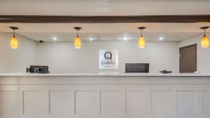 Un comptoir d’accueil avec une enseigne indiquant « Qualité garantie par Choice Hotels », un téléviseur à écran plat et une porte sur la droite.