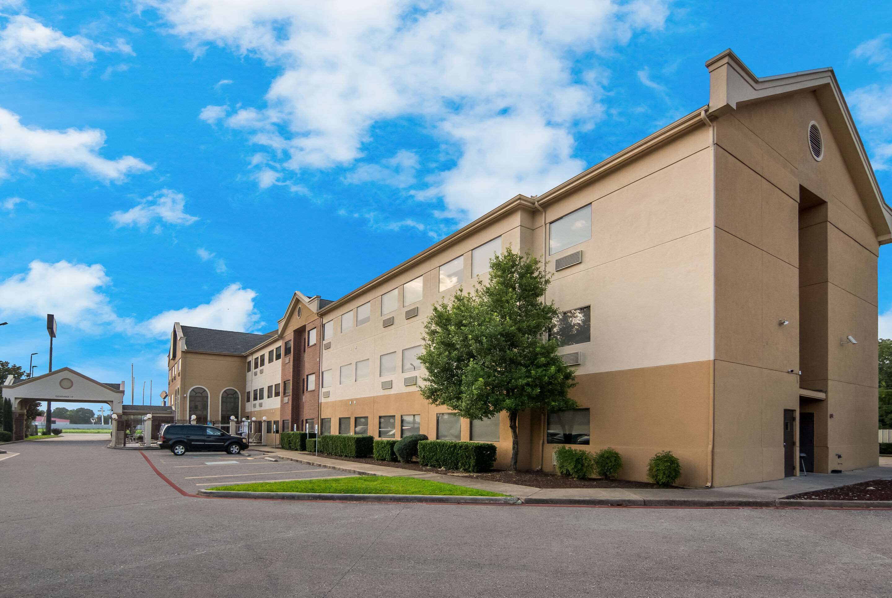 A modern hotel with a beige facade, multiple windows, and a parking lot.