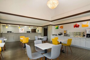 Um restaurante moderno com mesas e cadeiras brancas, uma área de cozinha e um letreiro com a palavra 'Quality'.