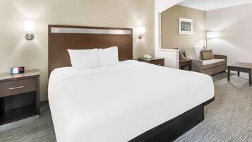 A hotel room with a large bed, bedside tables, a chair, and a desk.