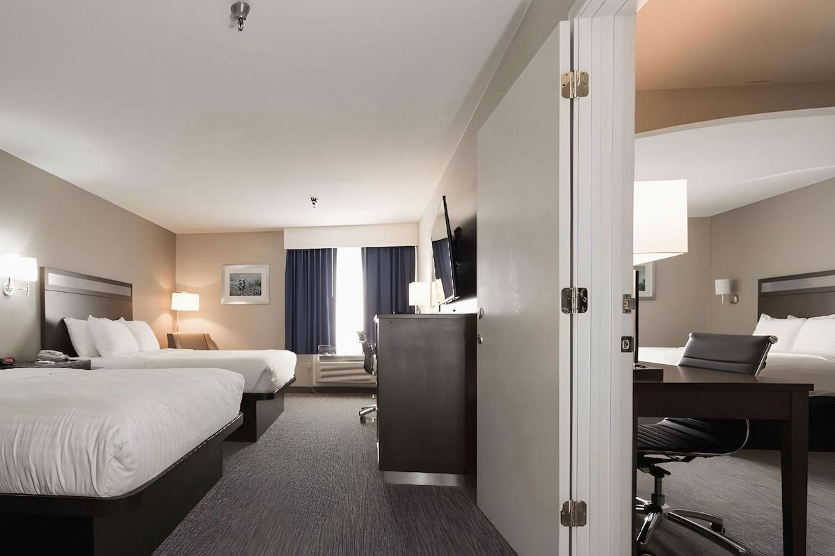 A hotel room with two beds, a desk, a TV, and a wardrobe.