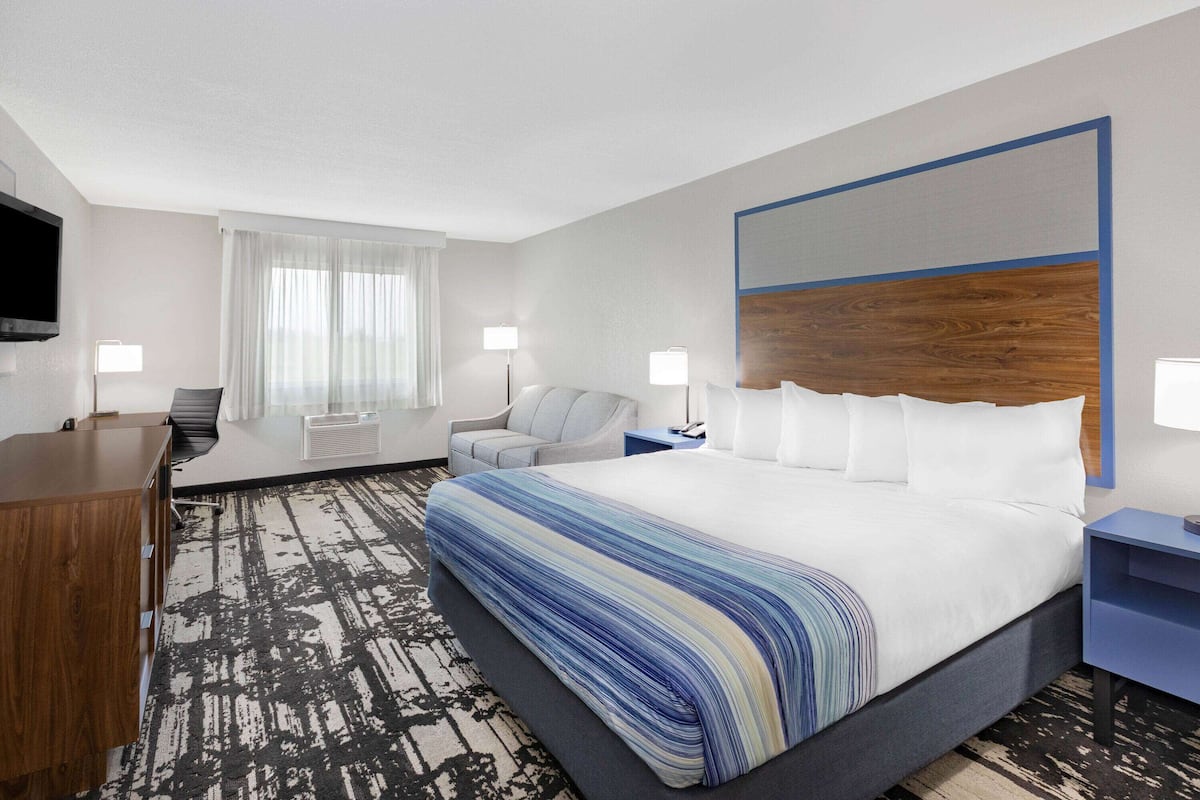 A hotel room with a large bed, a desk, a chair, and a TV.