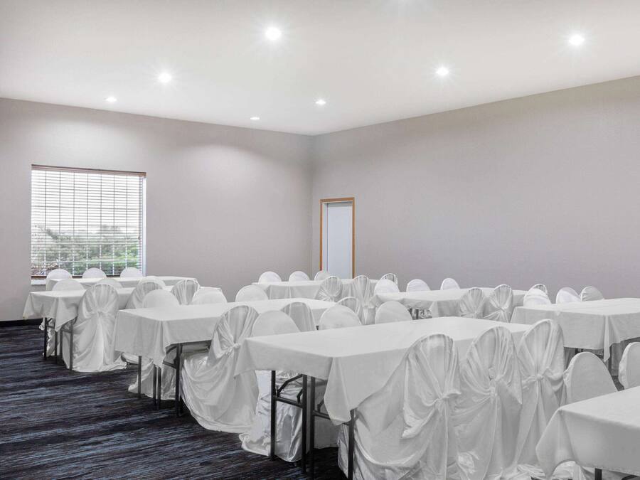 A conference room with multiple tables and chairs, a large window, and a door.