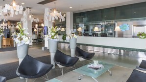 A modern lobby with black leather chairs, a reception desk, and large potted plants. - Holiday Inn Prague Congress Centre by IHG (Prague)