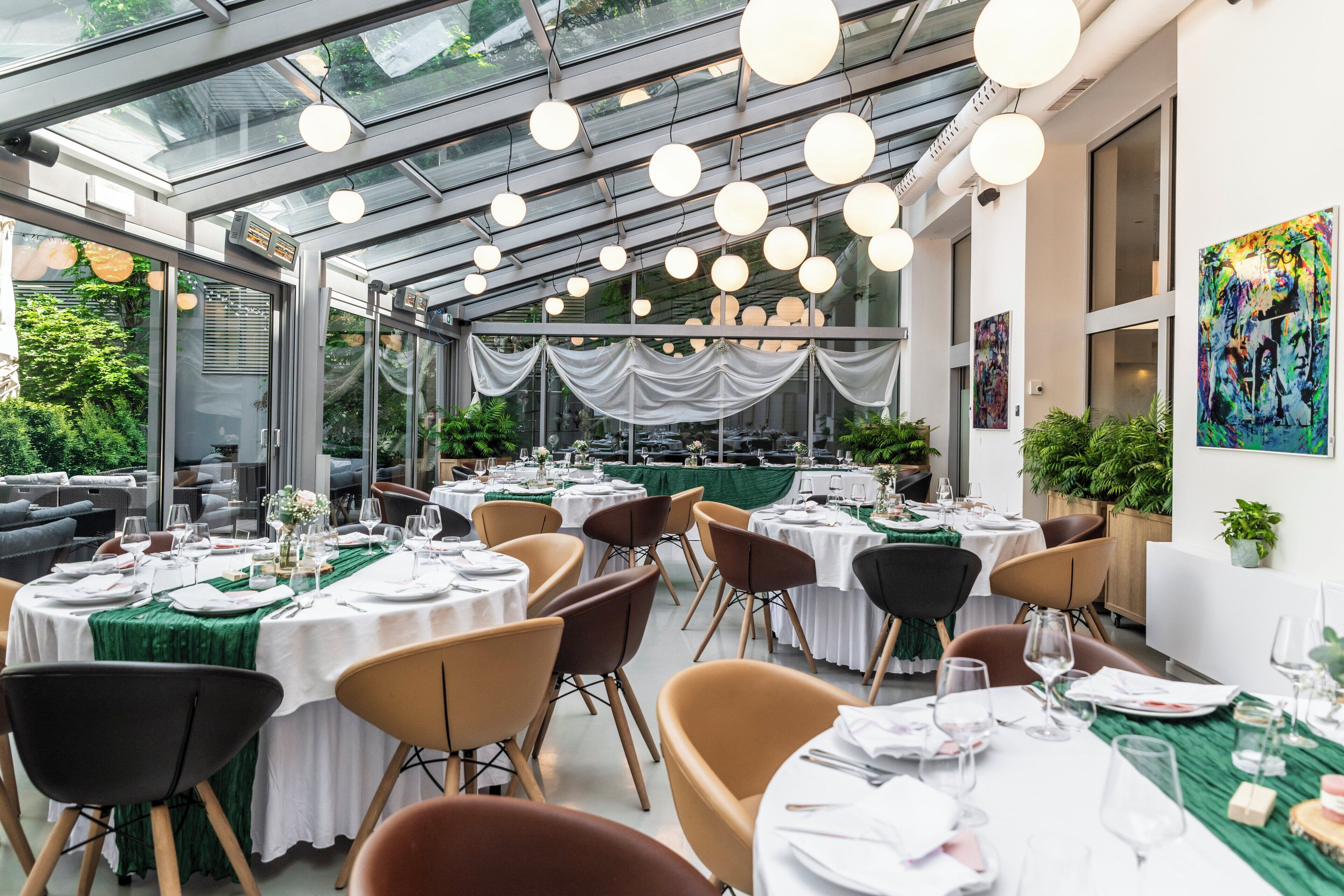 Un restaurante con mesas redondas, sillas y techo de cristal.