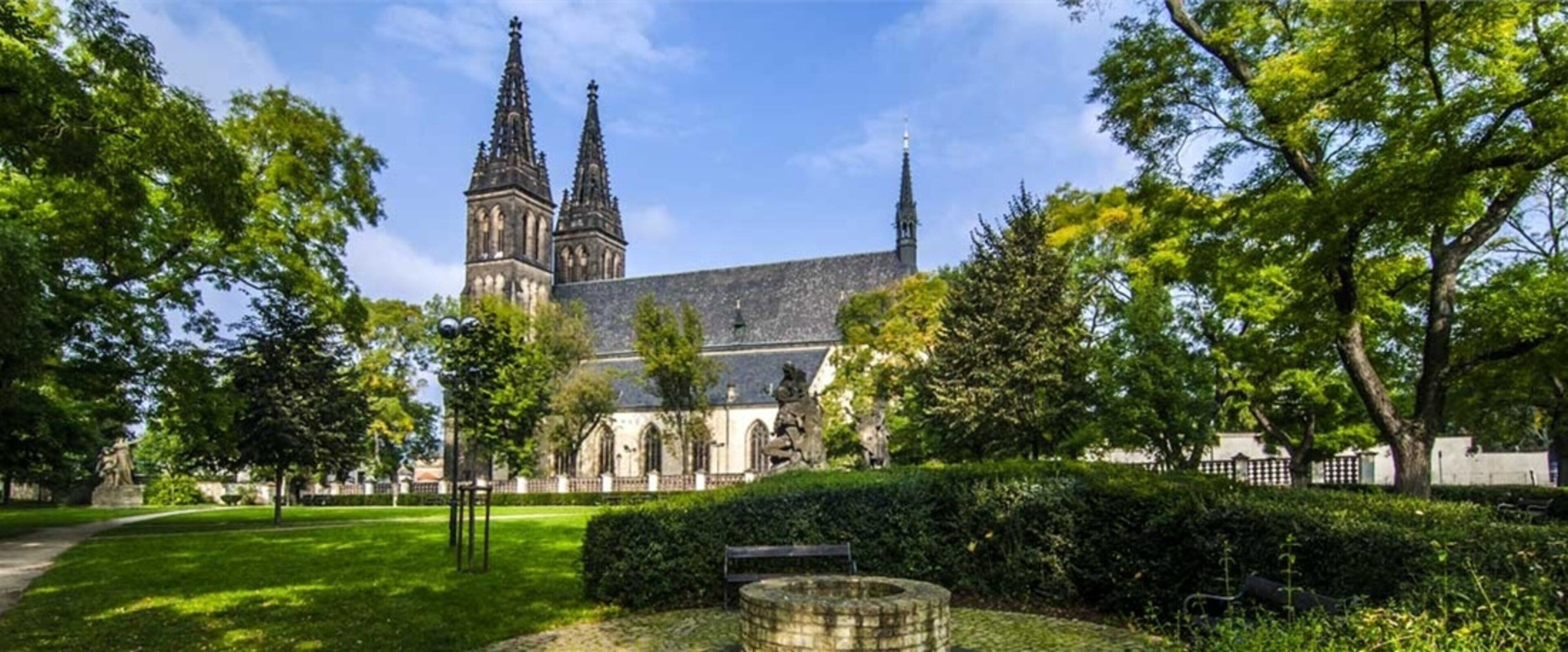 Una iglesia con dos torres, rodeada por un jardín cuidado y un sendero.