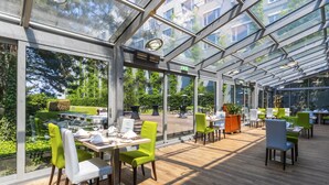 A modern restaurant with a glass roof, wooden flooring, and green chairs. - Holiday Inn Prague Congress Centre by IHG (Prague)