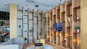 A modern living room with a grey sofa, wooden shelving units, and a television mounted on the wall. - Holiday Inn Prague Congress Centre by IHG (Prague)