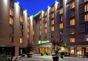 A Holiday Inn hotel with a modern facade, multiple floors, and a central courtyard with potted plants. - Holiday Inn Prague Congress Centre by IHG (Prague)