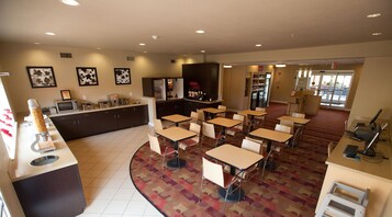 Eine Hotelhalle mit einer zentralen Rezeption, einer Sitzecke und einem Kühlschrank.