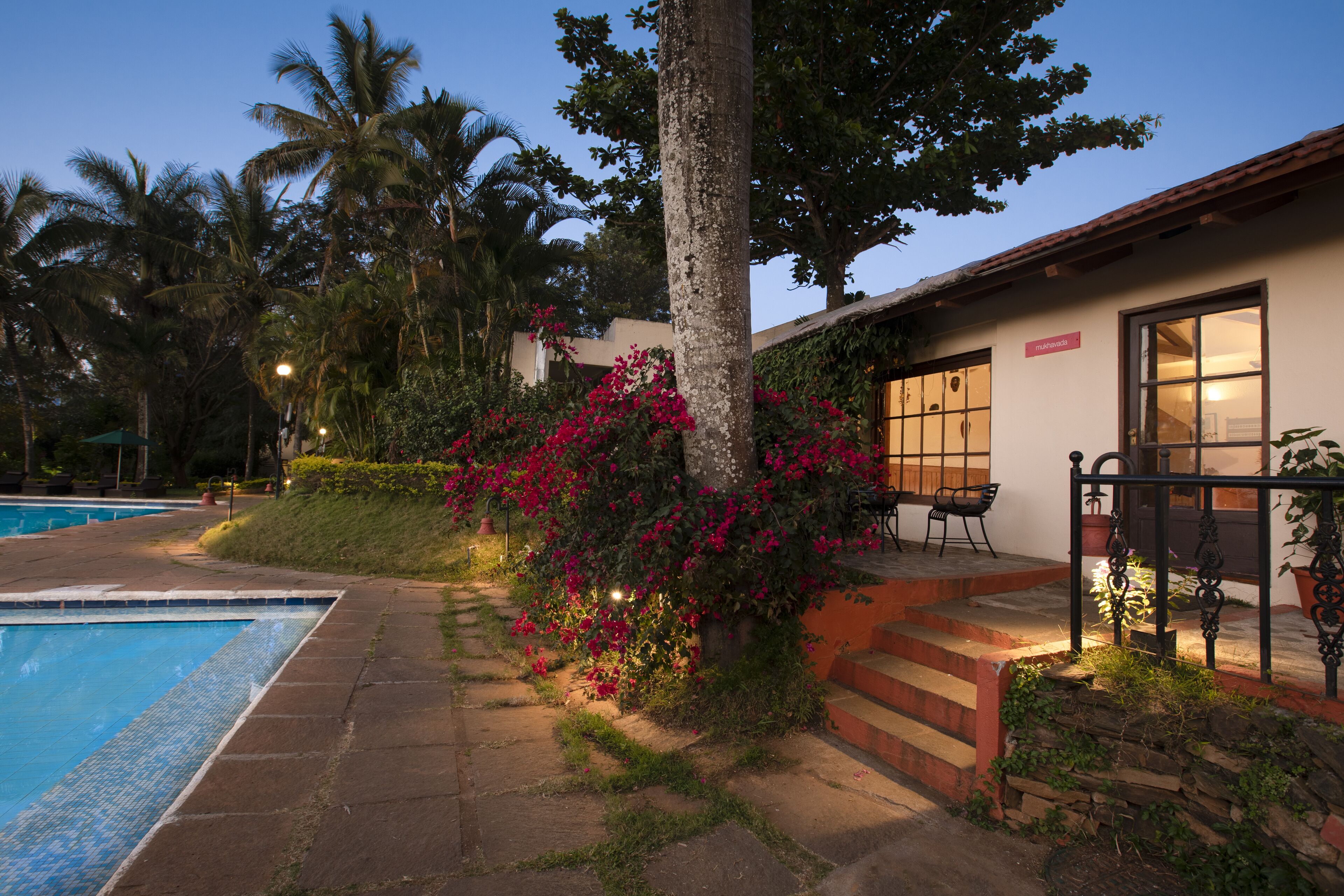 A poolside area with a palm tree, a small outdoor seating area, and a building with a sign that reads "Spa".