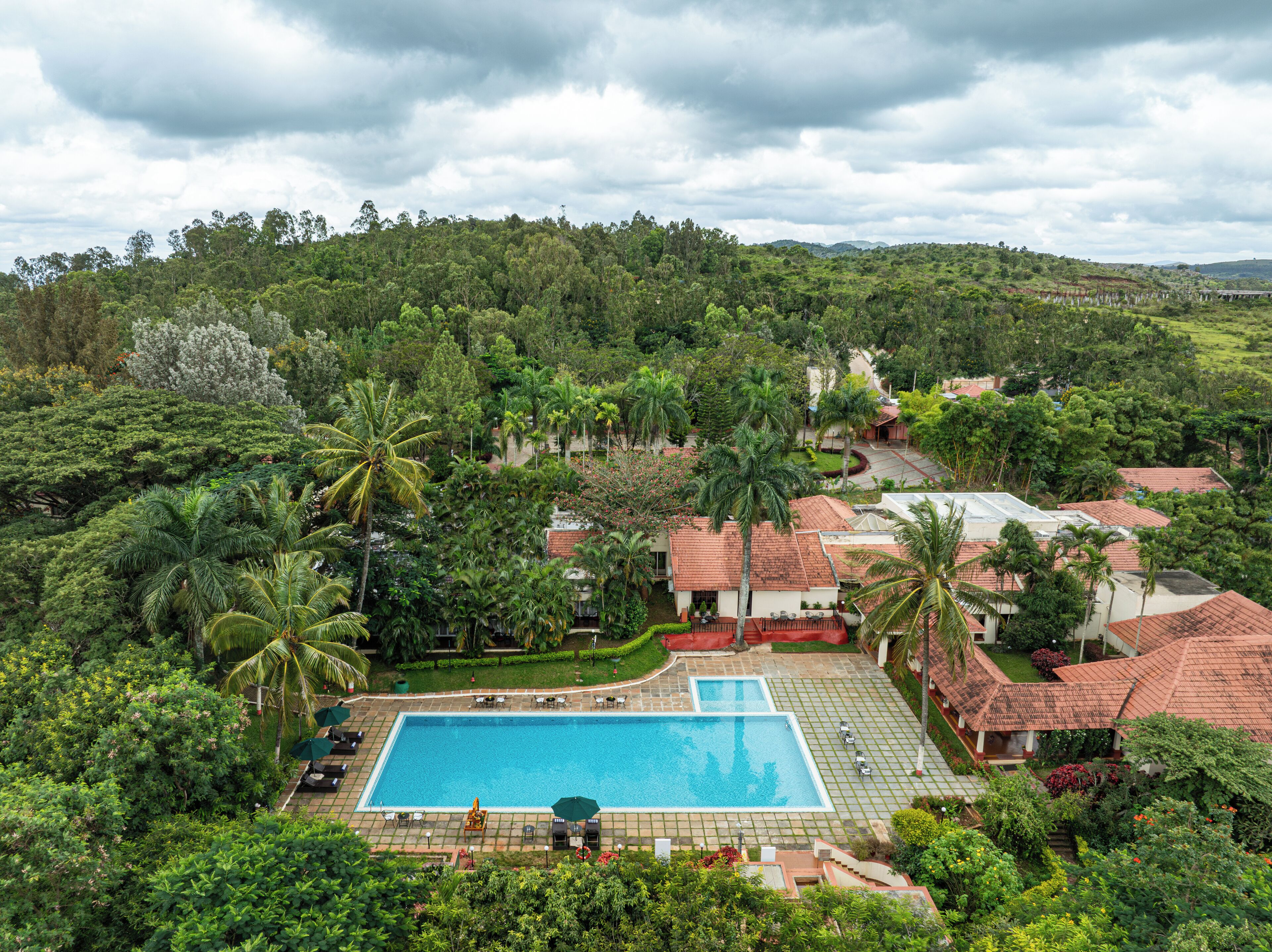 A resort with a swimming pool surrounded by lush greenery and palm trees.