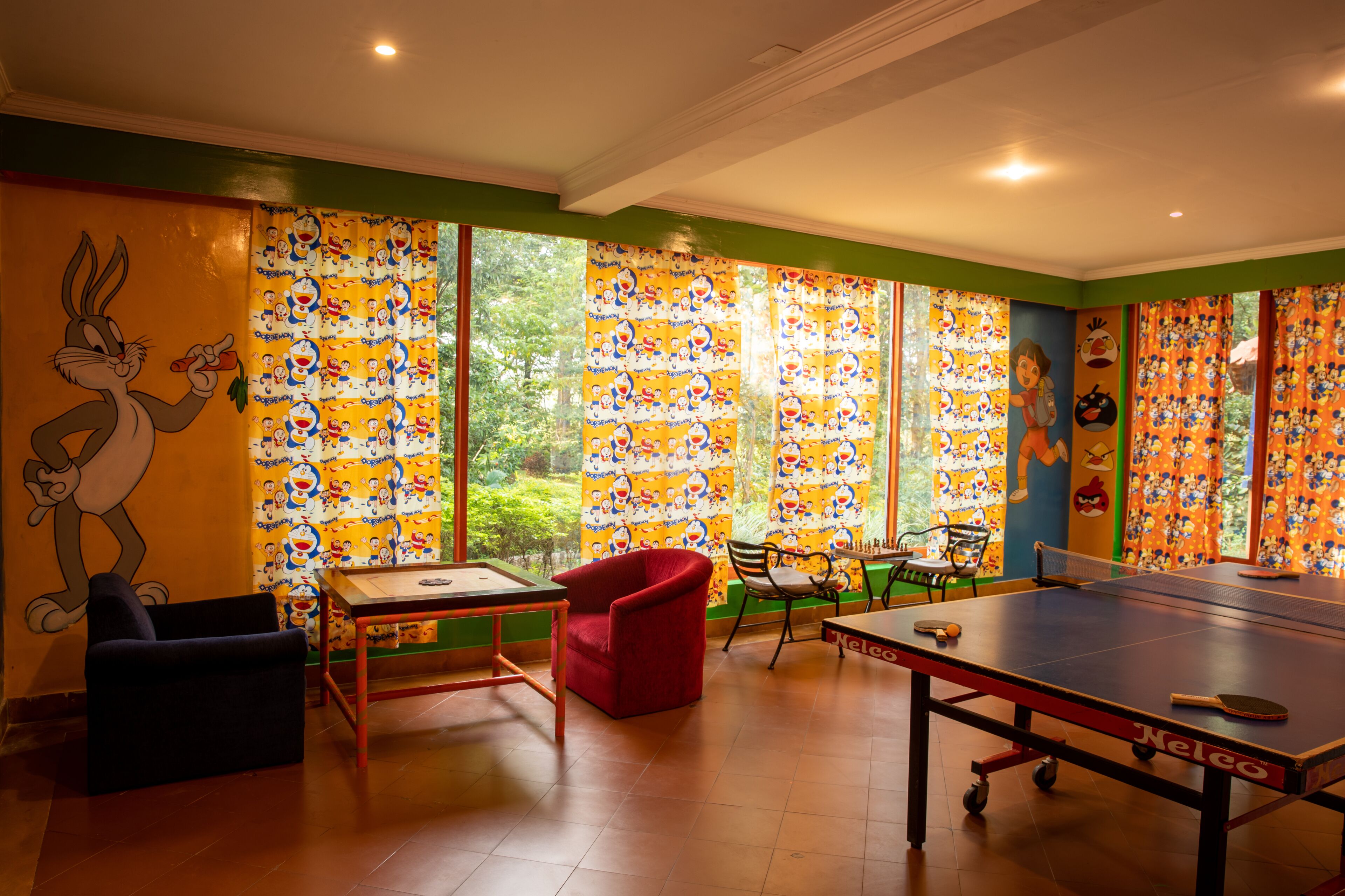 A room with a ping pong table, a red chair, and a table with a remote control.