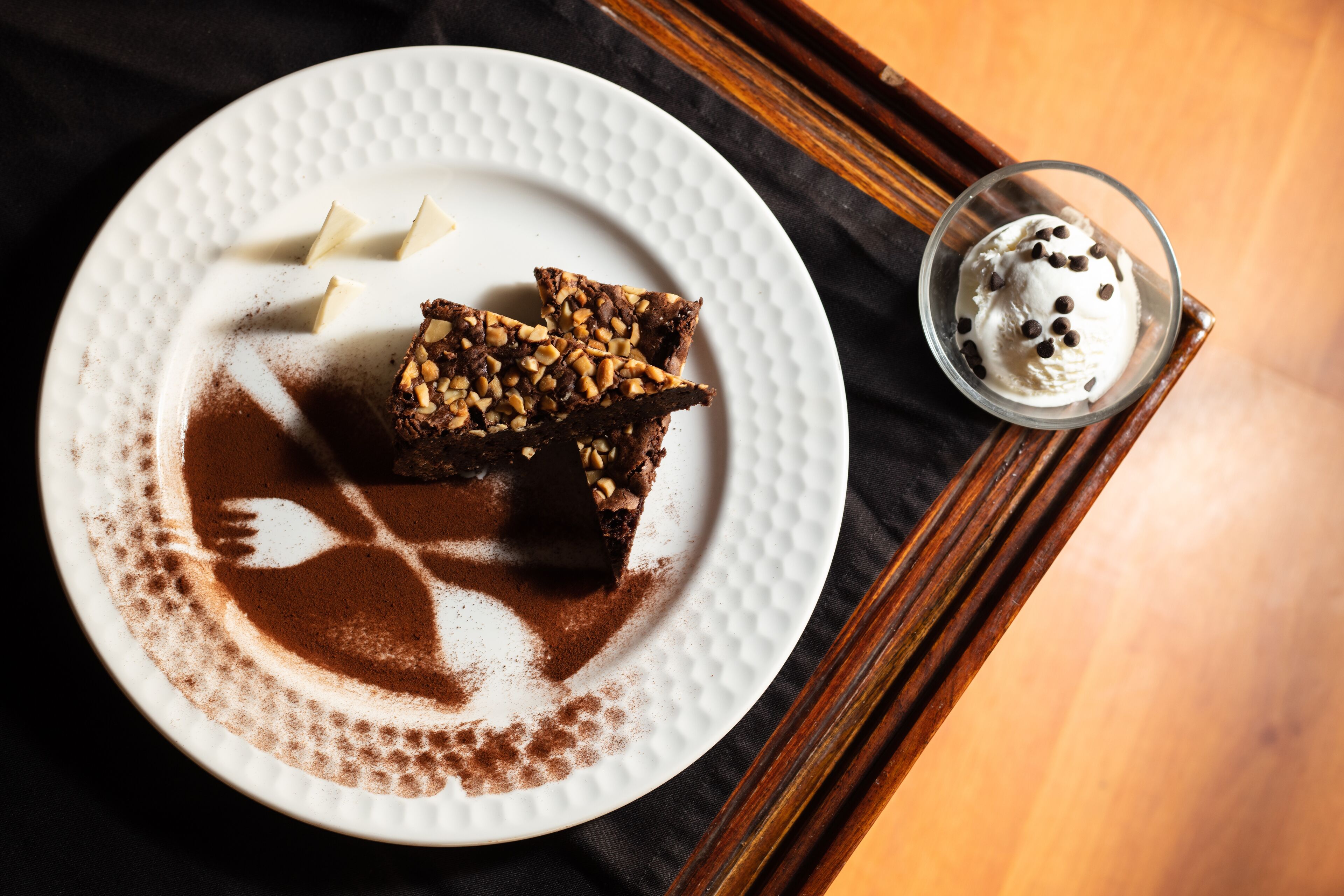 Een nagerechtbord met een brownie en een glas ijs.