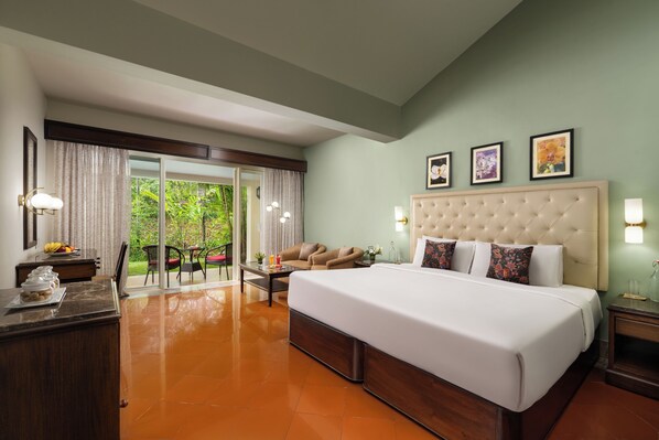 A hotel room with a large bed, a desk with a lamp, a chair, and a view of the outdoors.