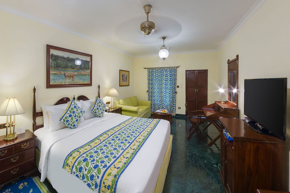 Une chambre d’hôtel équipée d’un lit, d’un bureau, d’une télévision et d’un ventilateur de plafond.