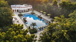 A resort with a large pool, sun loungers, and a view of the surrounding forest and mountains. - The Maharaja's Lodge, Ranthambore (Sawai Madhopur)