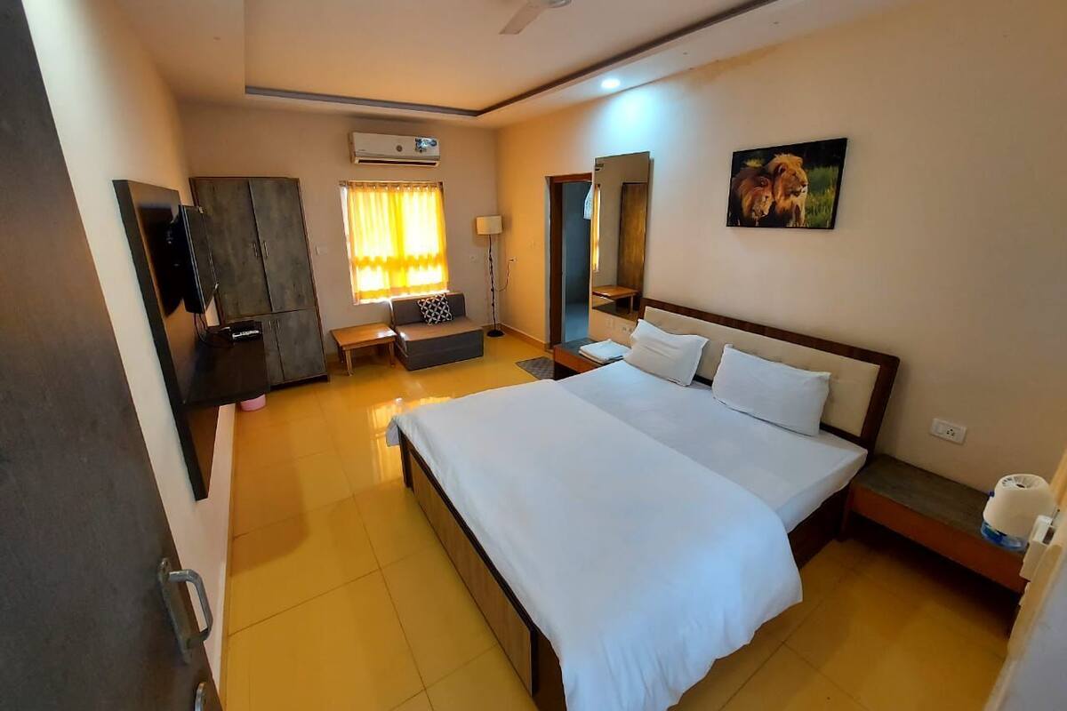 Una habitación de hotel con una cama grande, un escritorio, un armario, un ventilador de techo y un cuadro en la pared.
