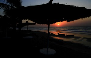Espreguiçadeiras, guarda-sóis, prática de vôlei de praia 