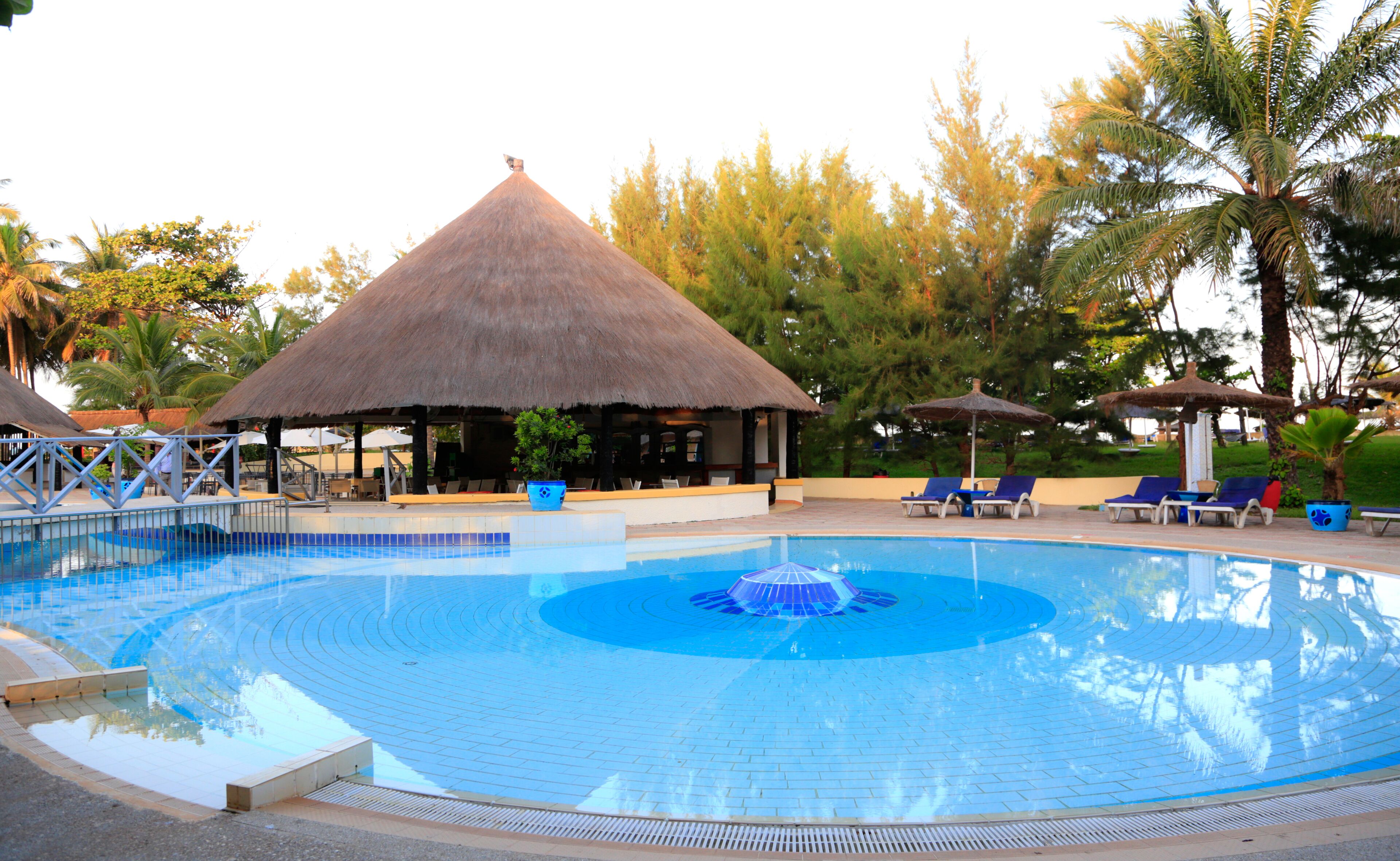 A swimming pool with lounge chairs and thatched-roof structures.