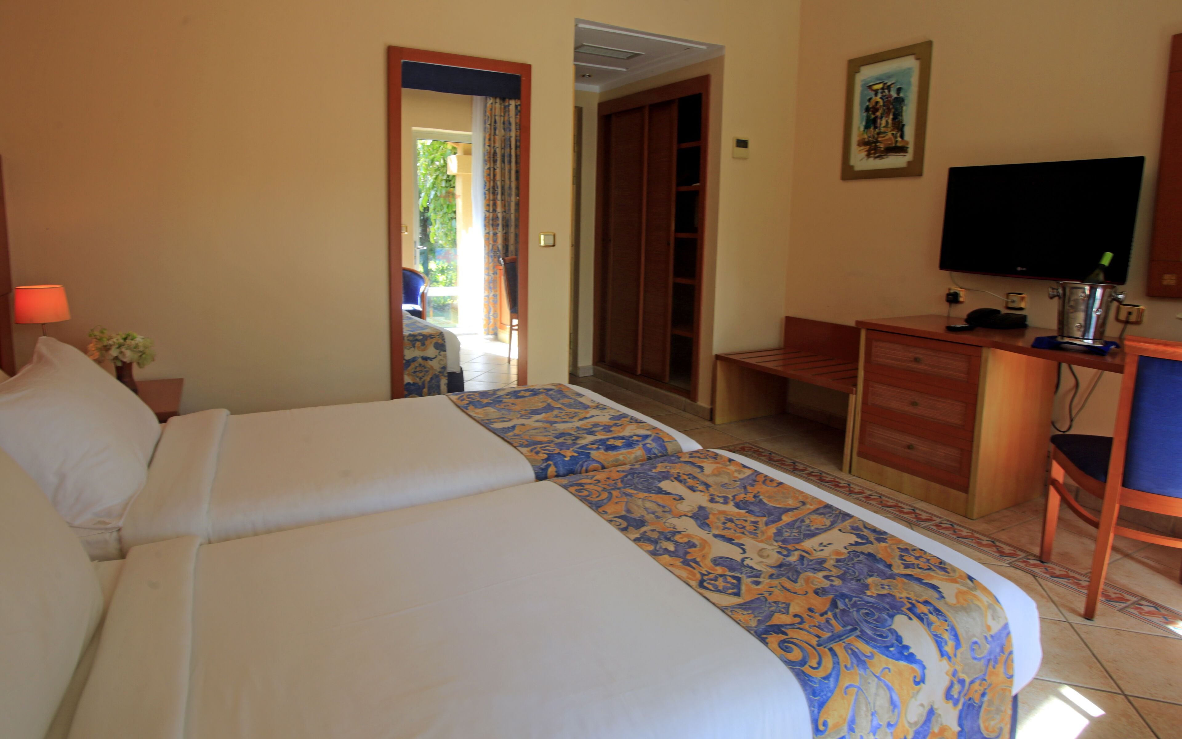 Habitación de hotel con dos camas, un escritorio, una silla, un televisor y un armario.