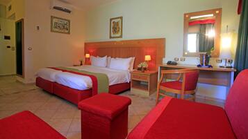 Habitación de hotel con una cama grande, un escritorio, una silla y una mesita.