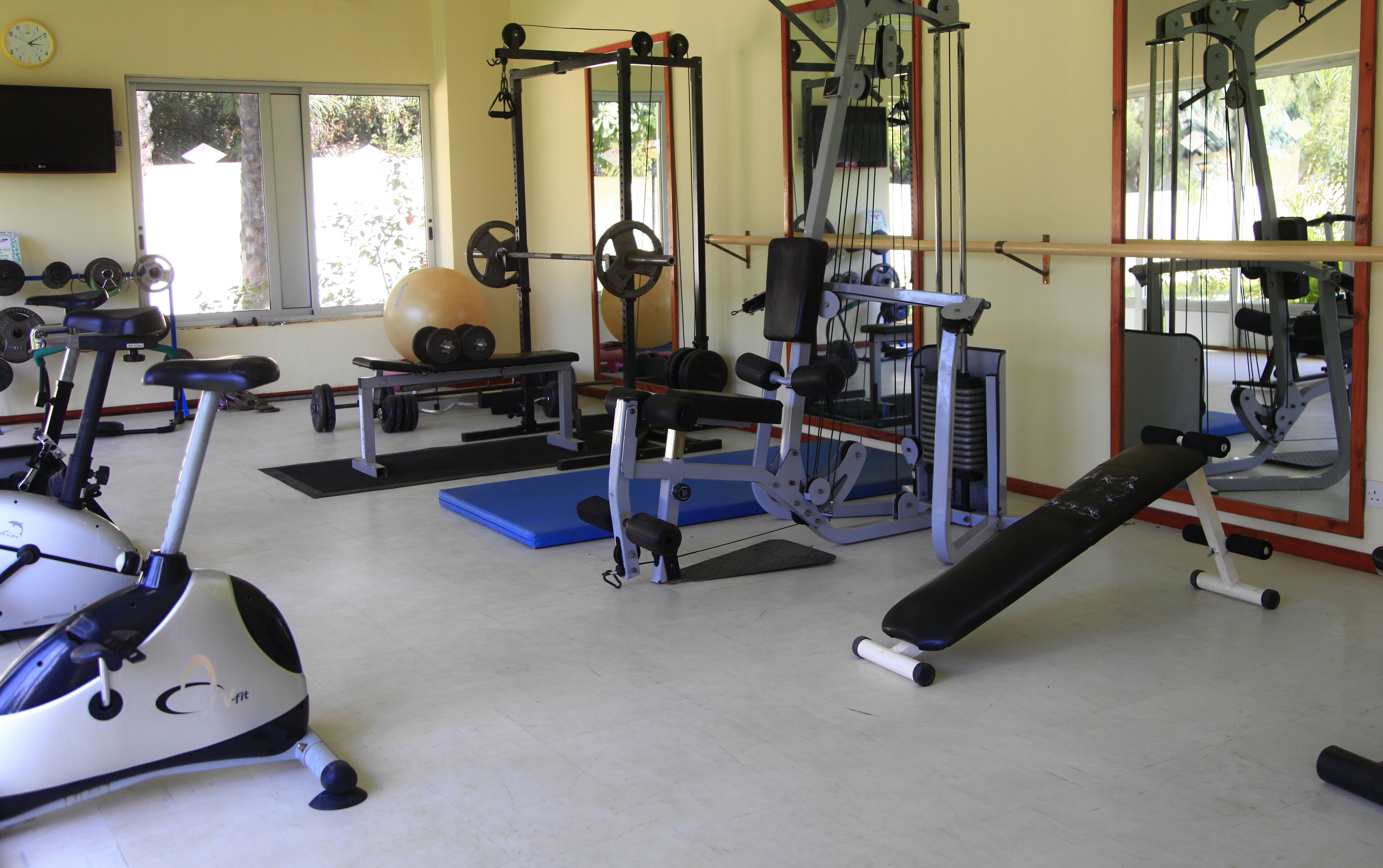 Een sportschool met diverse fitnessapparaten, waaronder een bankje, gewichten en een krachtapparaat.