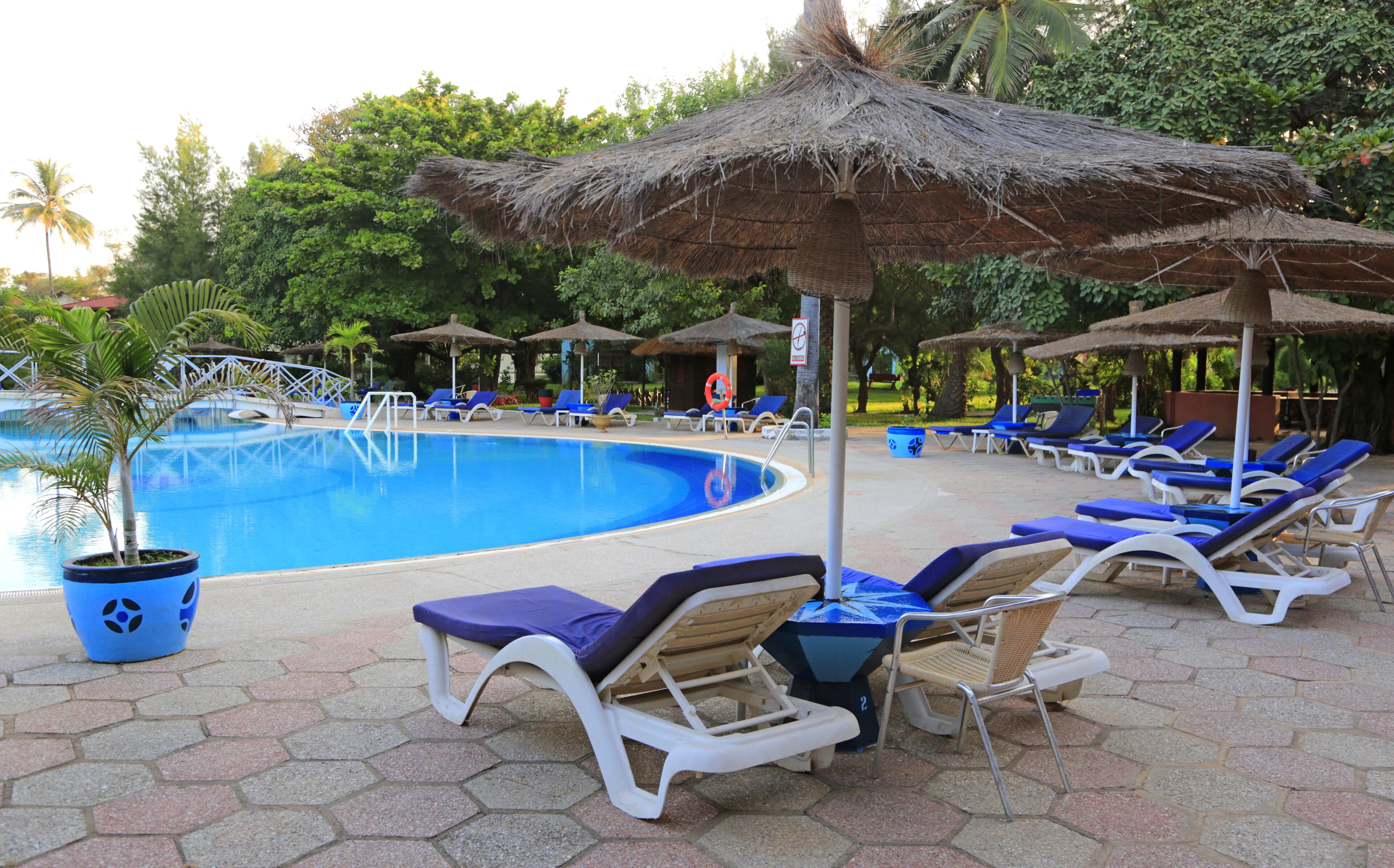 A swimming pool with lounge chairs and thatched umbrellas.