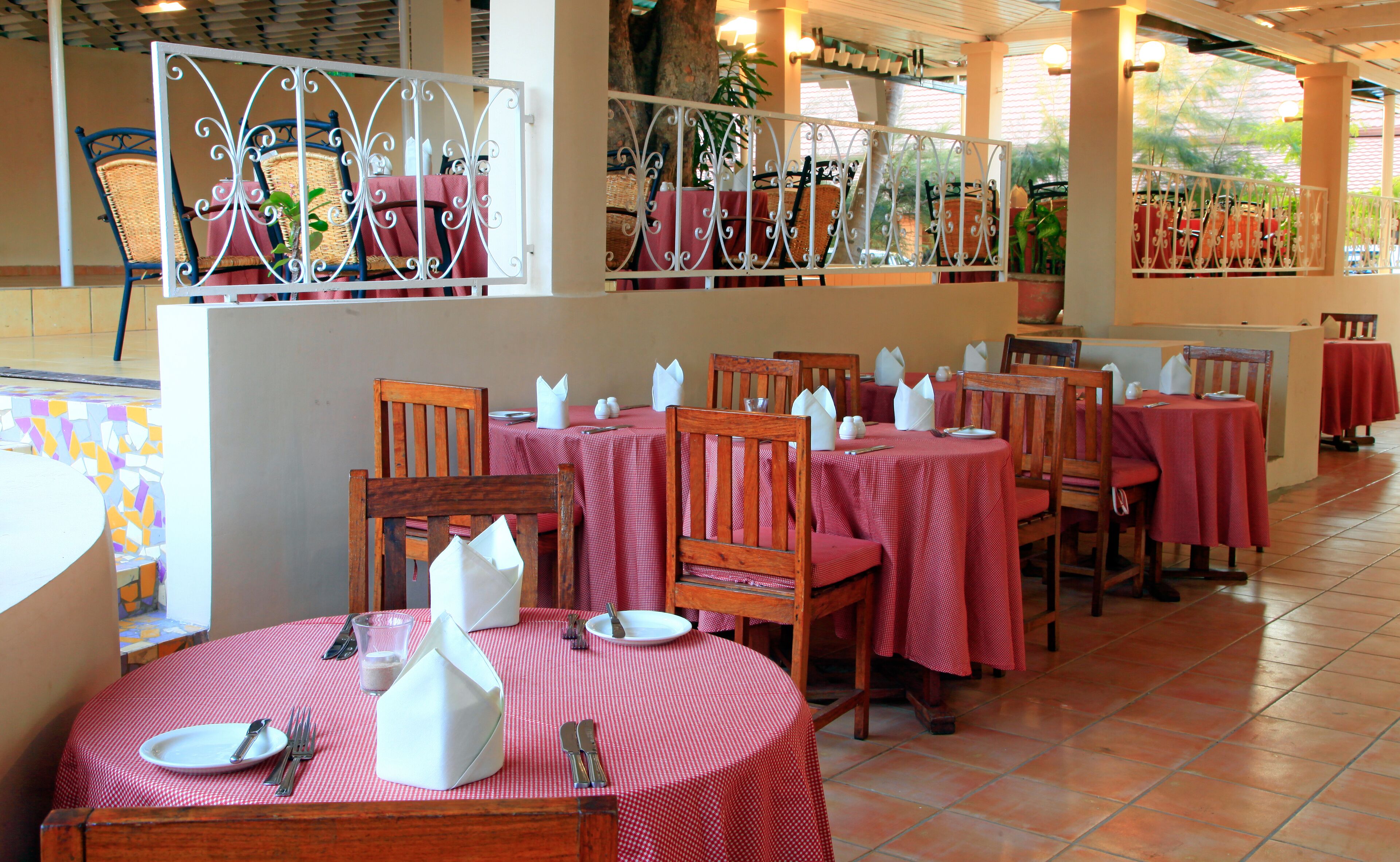 Ein Restaurant mit runden Tischen, bedeckt mit rot karierten Tischdecken, hölzernen Stühlen und weißen Servietten.