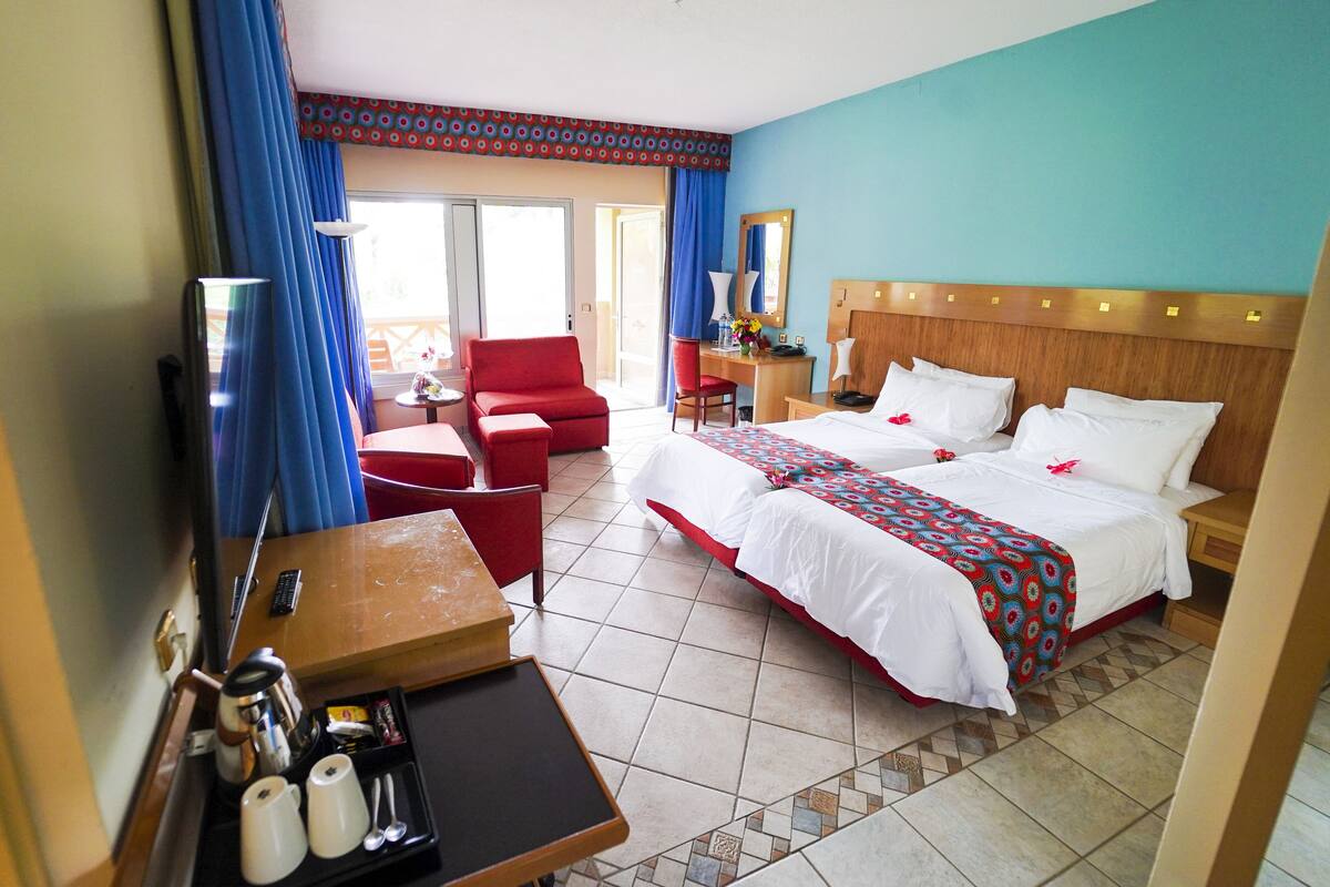 A hotel room with a bed, a desk, a chair, a TV, and a bathroom visible through an open door.