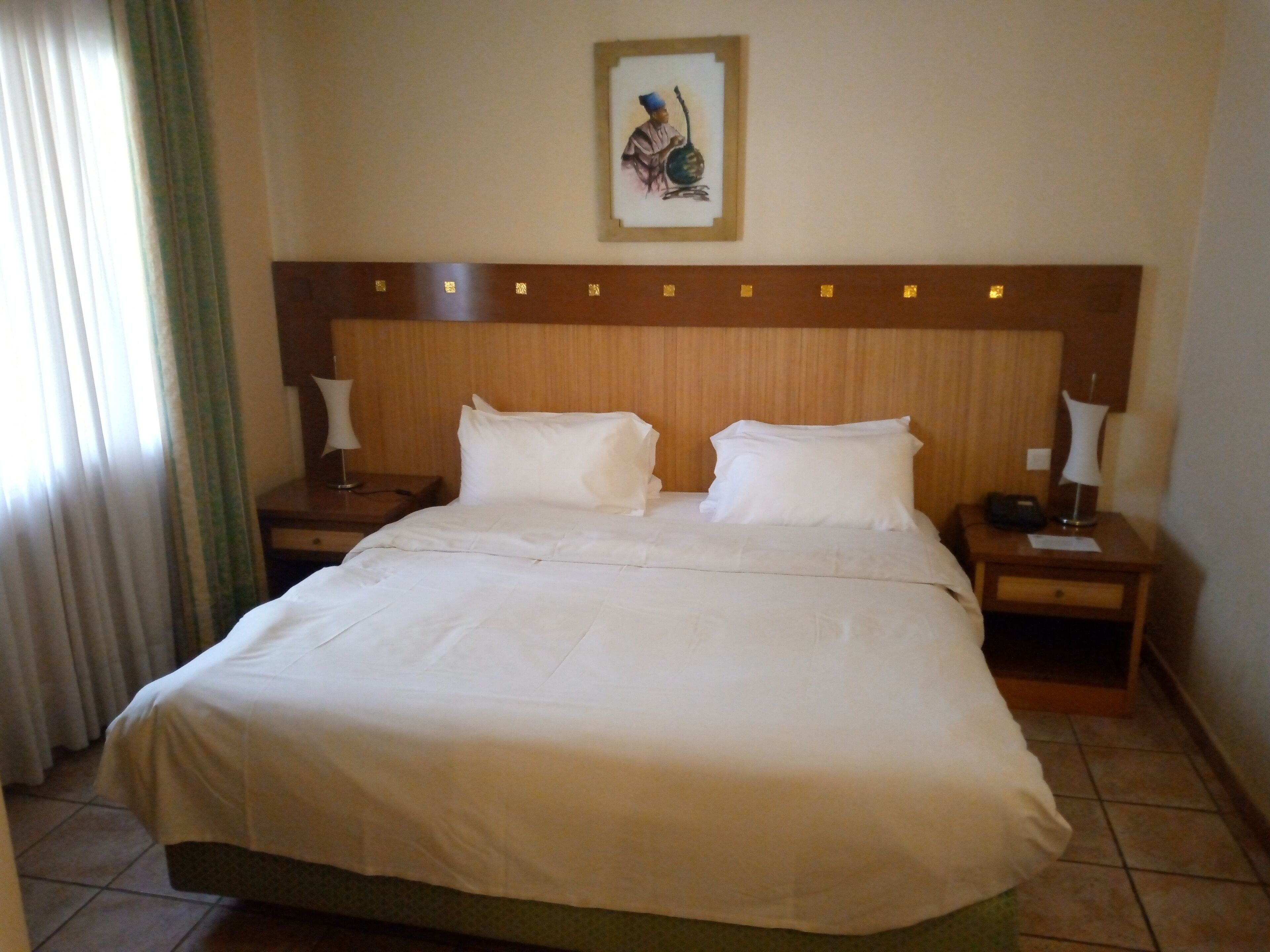 A hotel room with a large bed, two bedside tables, and a wall-mounted artwork.