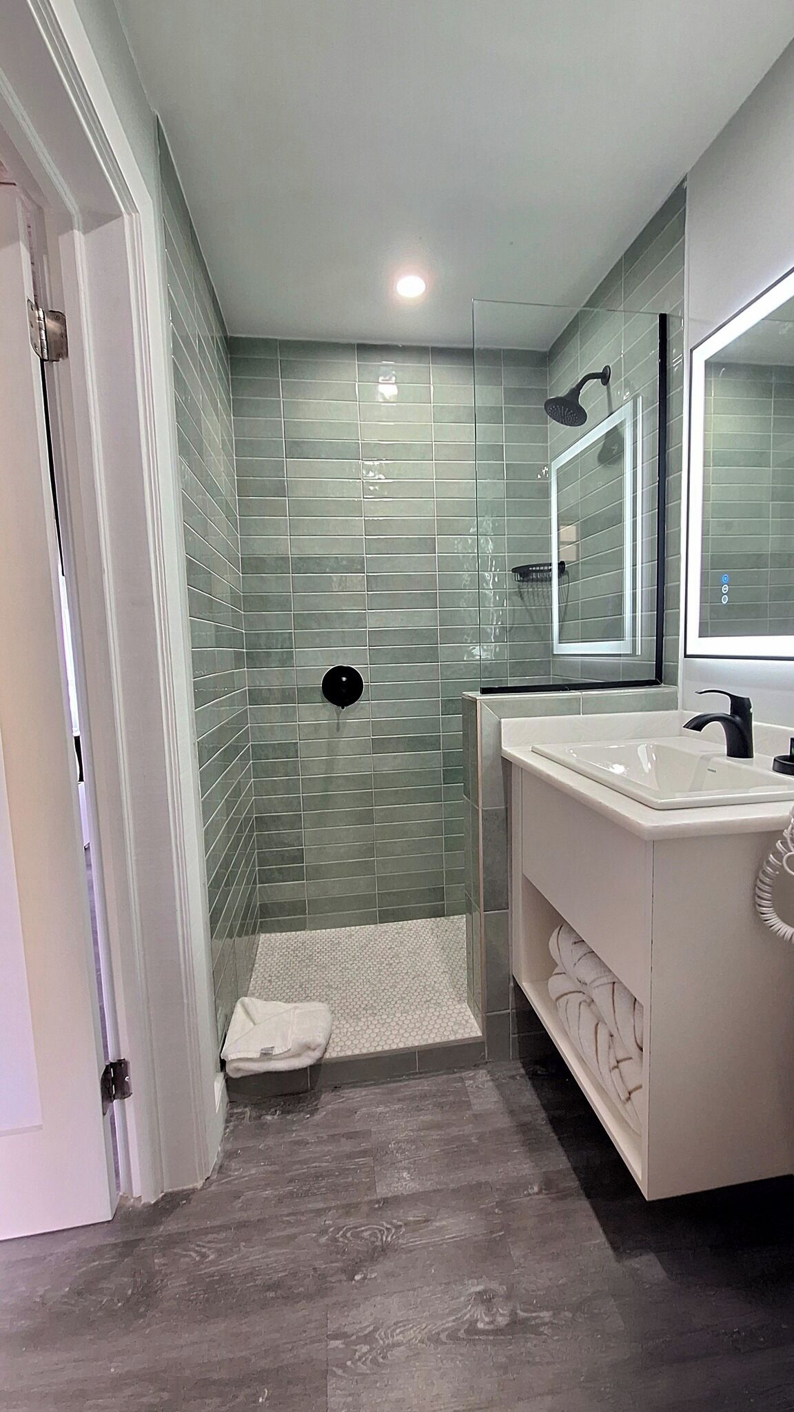 A modern bathroom with a glass shower, white vanity, and a large mirror.