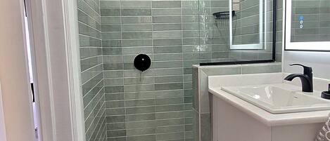 A modern bathroom with a glass shower, white vanity, and a large mirror.