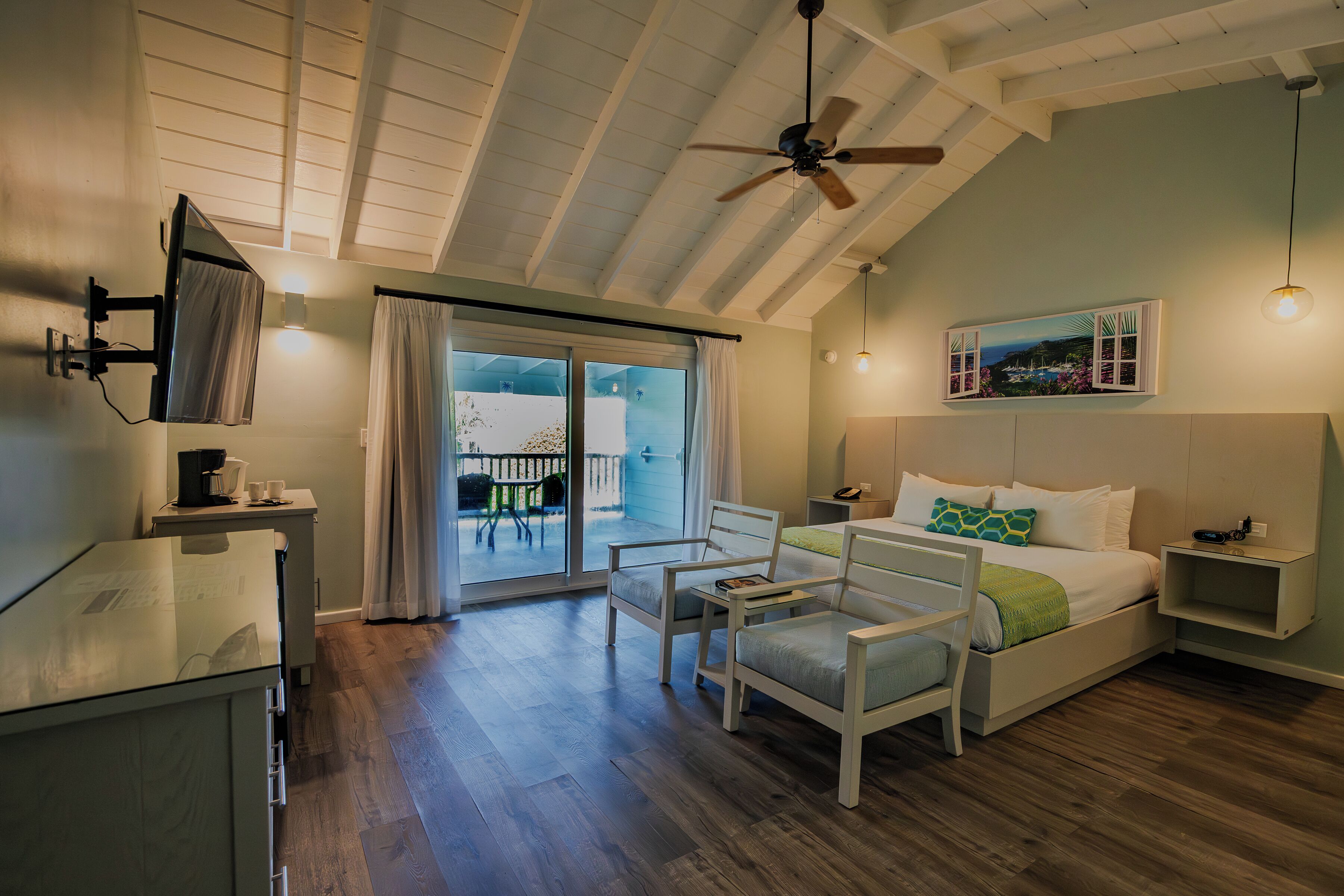 A bedroom with a bed, a desk, a chair, a ceiling fan, and a window with curtains.