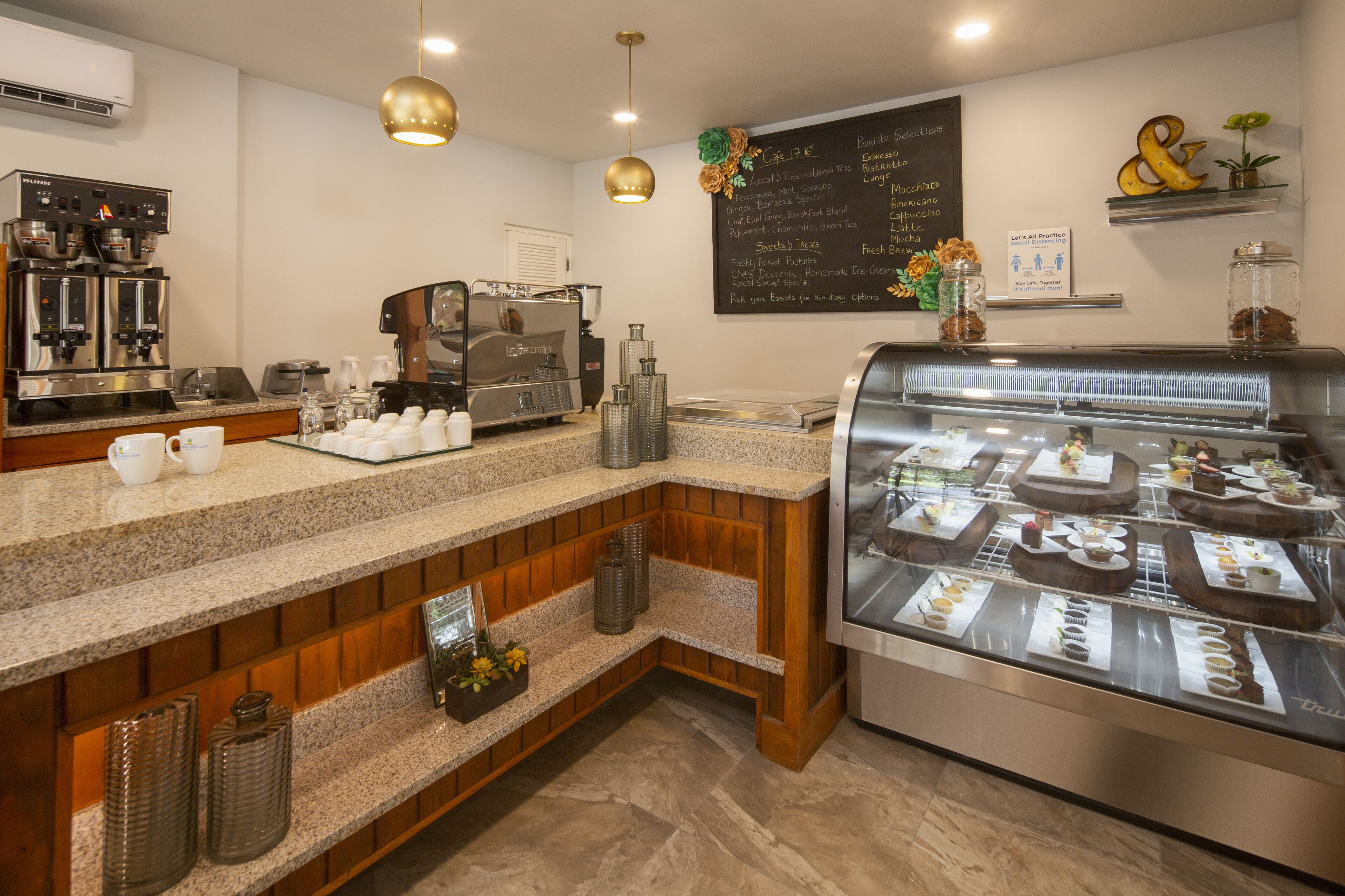 A coffee shop with a counter, espresso machines, a display case with pastries, and a chalkboard menu.