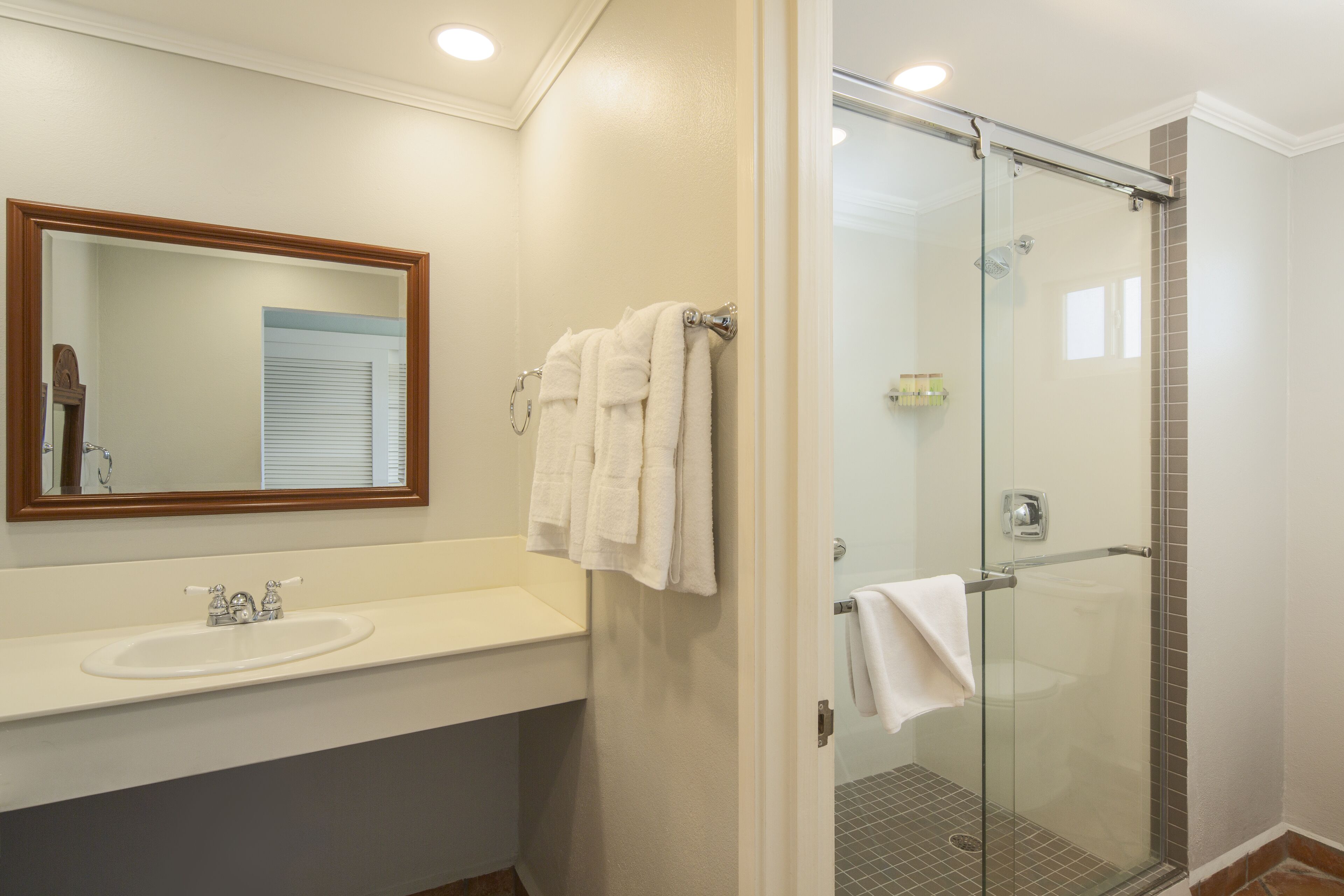 A bathroom with a sink, mirror, and glass shower enclosure.