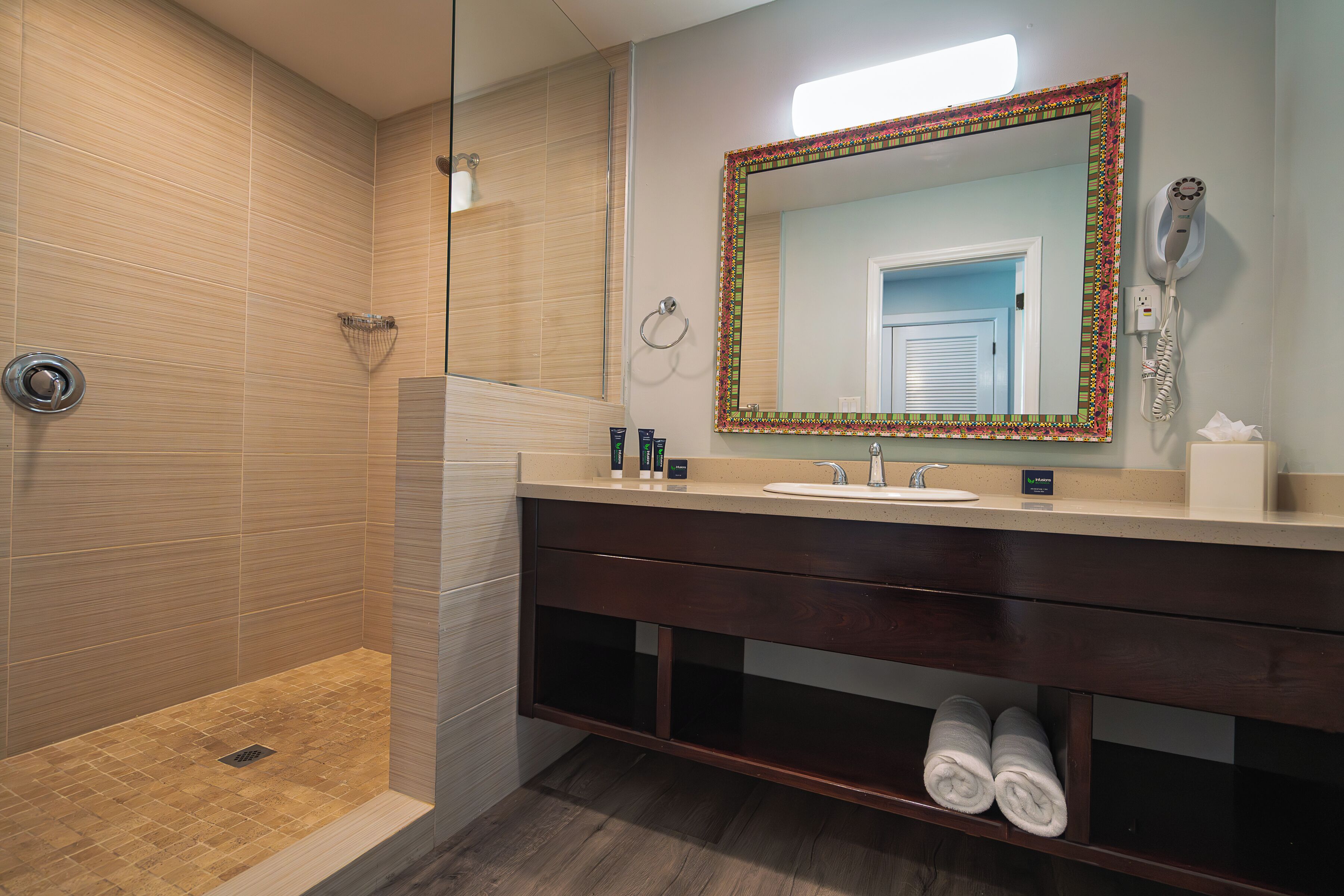 A modern bathroom with a shower, vanity, and a large mirror with a decorative frame.