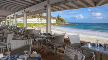 A beachside restaurant with outdoor seating overlooking the ocean.