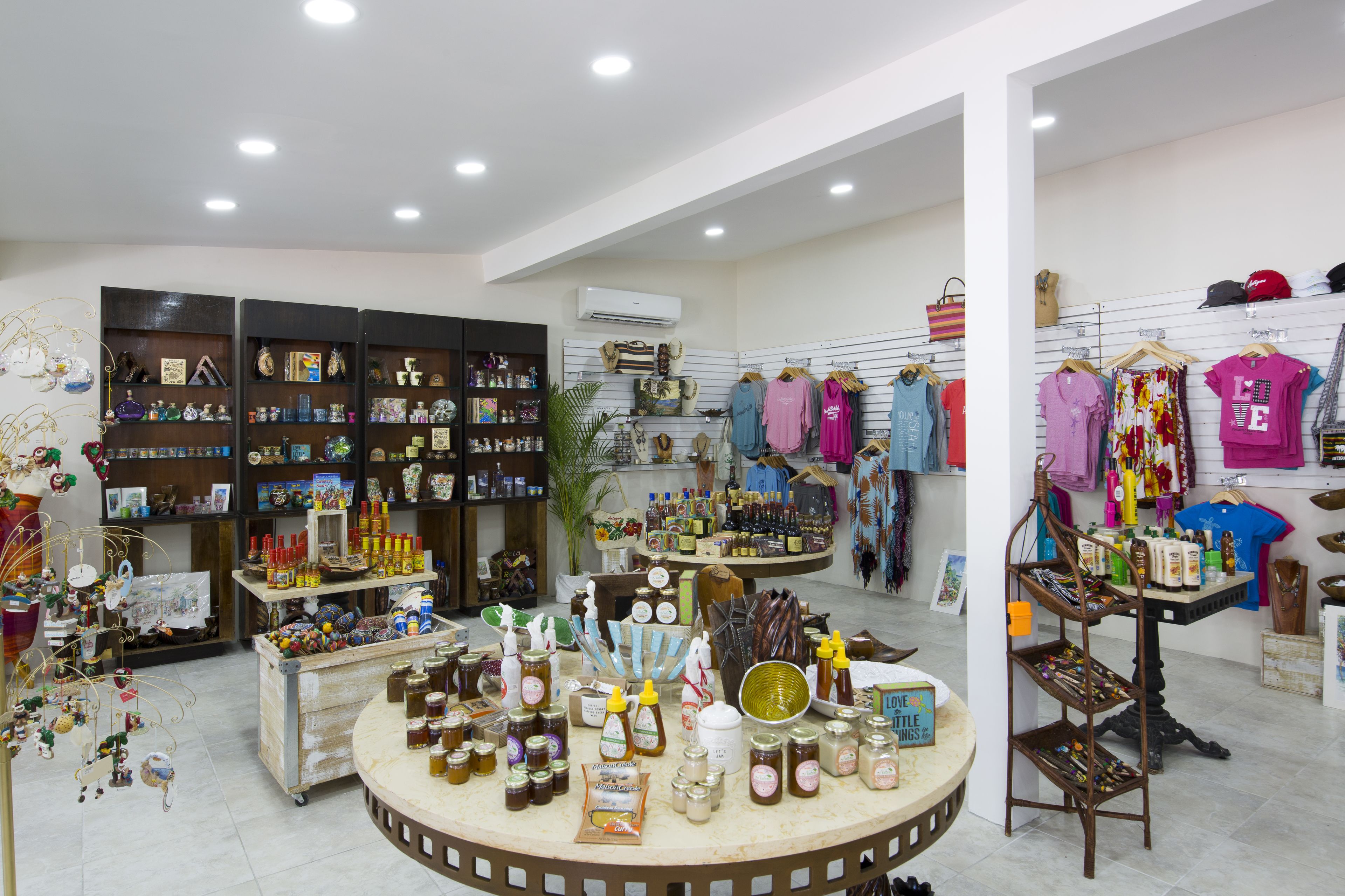 A well-lit store with shelves of various items, a display of clothing, and a counter with jars of honey.