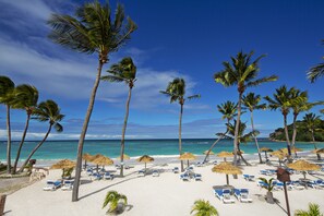Am Strand, weißer Sandstrand, Liegestühle, Sonnenschirme