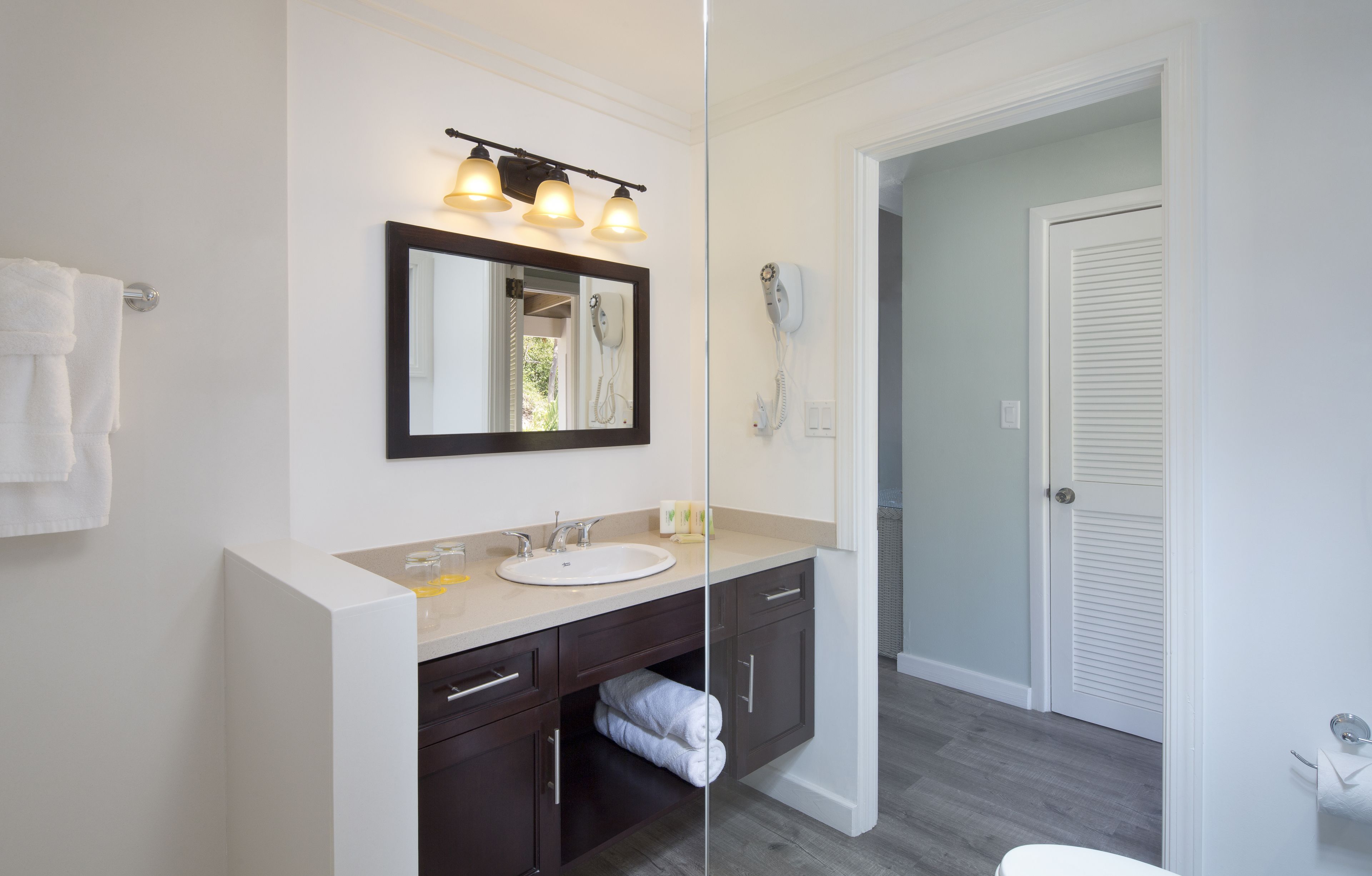 Une salle de bain moderne avec un grand miroir, un lavabo et un sèche-cheveux.