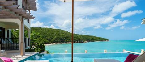 Piscina infinita con vistas a una playa y al océano.