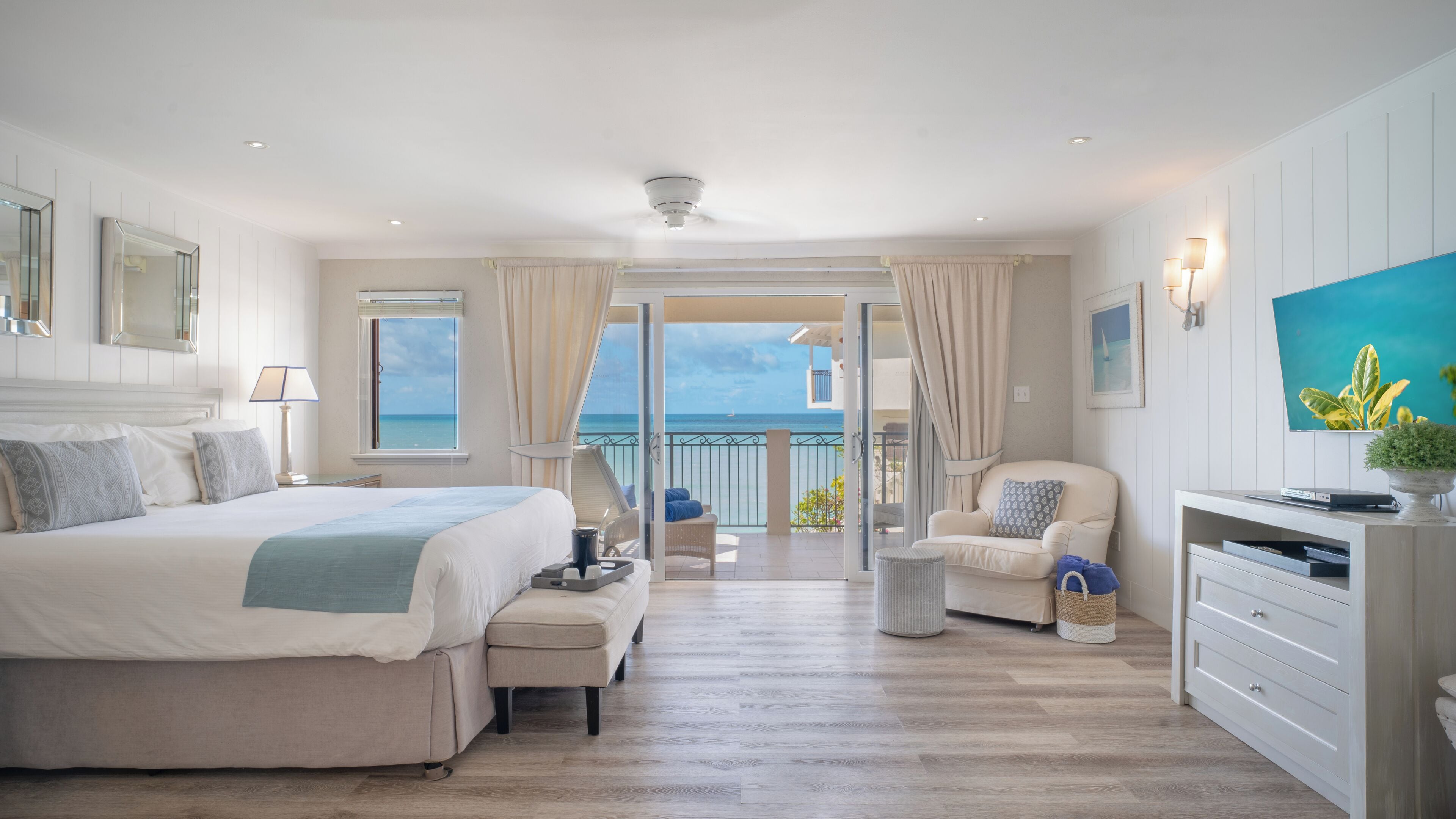 Ein geräumiges Schlafzimmer mit einem großen Bett, einer Sitzecke mit Meerblick und einem Balkon mit Meerblick.
