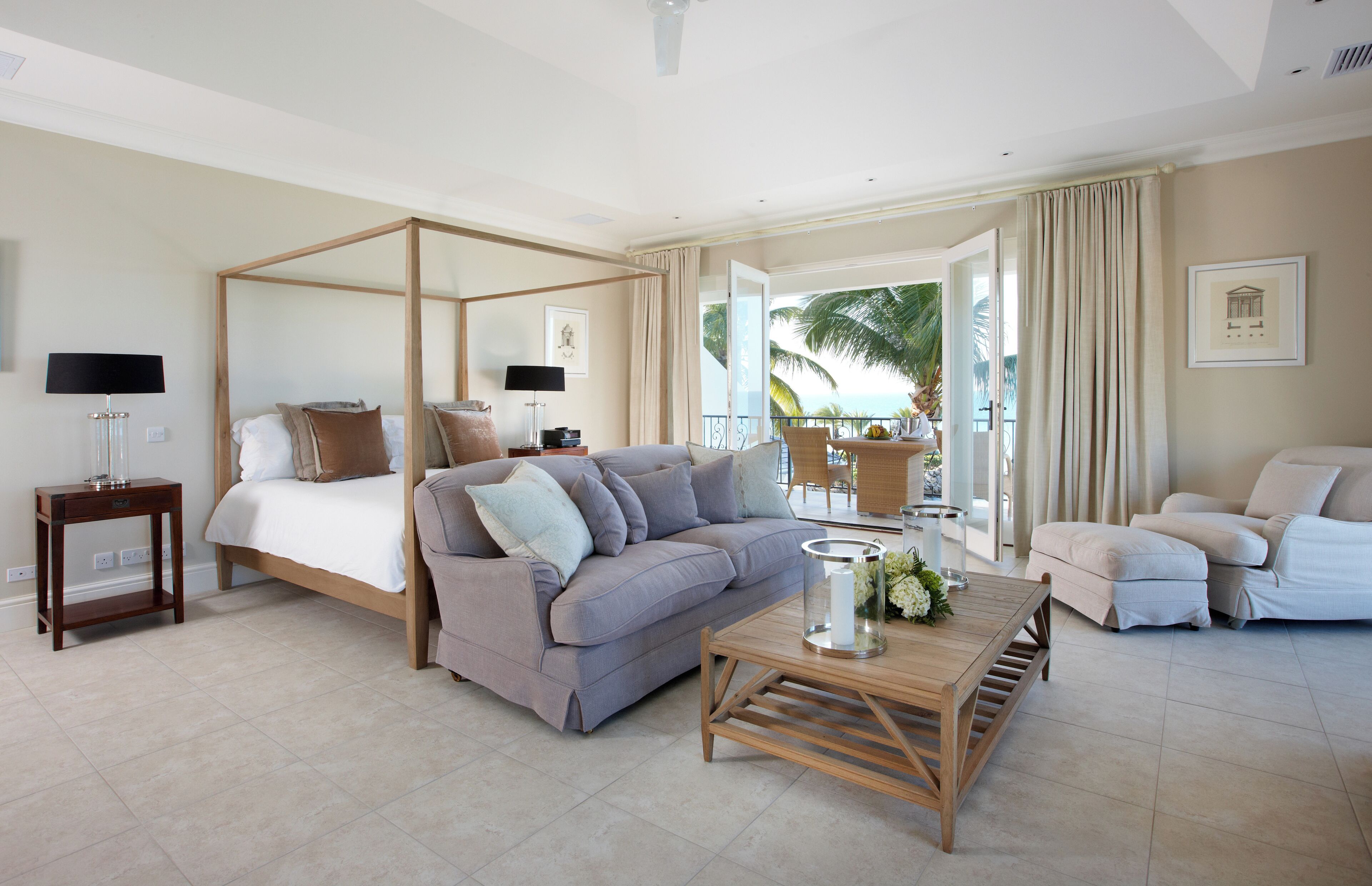 A spacious room with a four-poster bed, a sofa, a coffee table, and a chair.